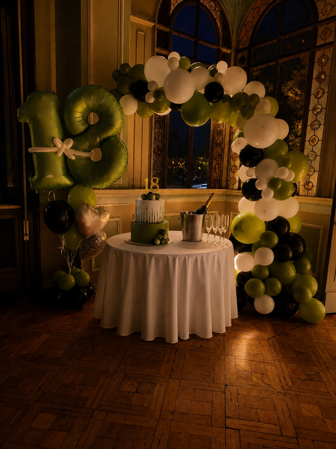 Allestimento 18 anni con arco organico di palloncini verde salvia bianco e nero, numeri giganti 18 e tavolo torta in elegante location a Legnano